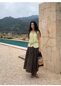 Woman in a pale yellow V-neck knitted vest with mesh details in outdoor setting
