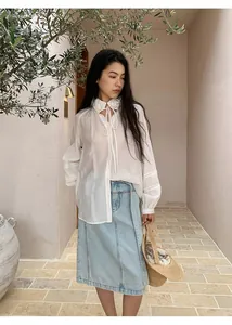 Lifestyle shot of an Asian model in a white floral blouse and light blue denim midi skirt.