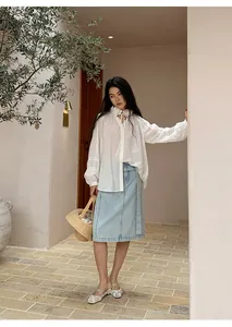 Asian model in a stylish light blue straight denim skirt and white ruffle blouse