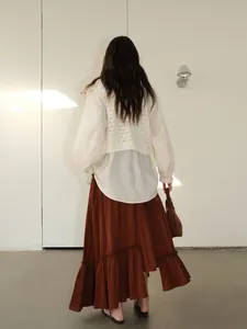 Back view of a woman wearing an irregular tiered brown maxi skirt and white shirt