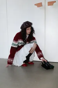 Detalle de falda corta plisada blanca con cintura elástica y cárdigan rojo acogedor