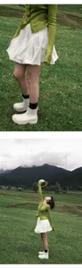 Minifalda plisada blanca con cintura elástica y cárdigan verde en un prado natural