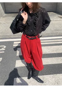 Détail mode de ce pantalon large rouge vif porté avec un chemisier noir en dentelle
