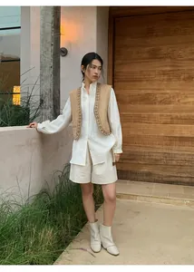 Model wearing cream linen wide-leg shorts with matching belt in a rustic outdoor setting