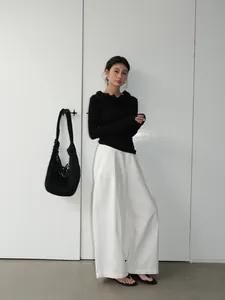 Elegant women's white wide-leg trousers styled with a minimalist black long-sleeve top