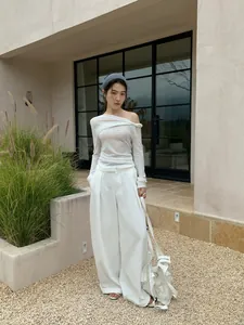 Modern minimalist white off-shoulder pleated wrap top paired with elegant wide-leg trousers set