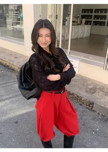 Mannequin portant un pantalon large rouge brossé associé à un haut en dentelle noire