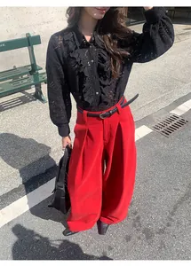 Vue détaillée du pantalon large en denim rouge porté avec une chemise en dentelle noire