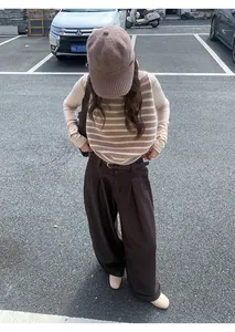 Vue complète d'un jean marron large décontracté porté avec un gilet à rayures et une casquette.