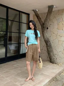 Modell trägt stilvolle braune Leinen-Shorts mit weitem Bein und Gürtel im Garten