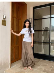 Stylish woman wearing vintage brown checkered loose harem pants in outdoor setting