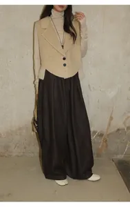 Gros plan sur un pantalon en jean brossé ample assorti à un gilet en laine beige