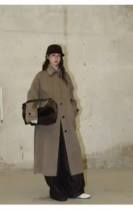 Photo de mannequin portant un manteau long et un pantalon en jean brossé à jambe large.