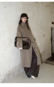 Femme chic portant un manteau en laine marron et un jean large dans un décor industriel.