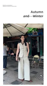 Full view of minimalist beige vest and wide-leg trousers outfit in a vintage street setting