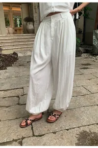 White loose Tencel wide-leg harem pants shown in a casual outdoor lifestyle setting