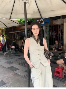 Woman wearing minimalist high-waisted wide-leg cotton blend trousers in a street cafe setting