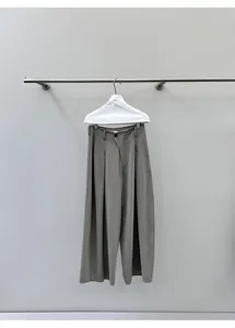 Detailed view of casual olive green wide-leg denim trousers hanging on a metal rod
