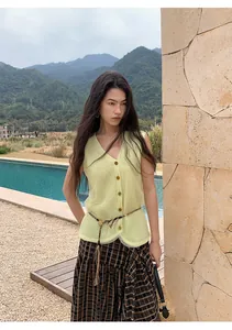 Detail view of a pale yellow mesh knit vest on a model in a scenic outdoor environment