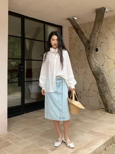 Fashionable woman wearing a light blue straight denim midi skirt for casual summer outdoor style