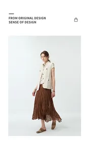 Full view of brown textured pleated bias cut skirt paired with a beige vest