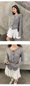Detalle de minifalda de tablas blanca con cintura elástica y cárdigan gris.