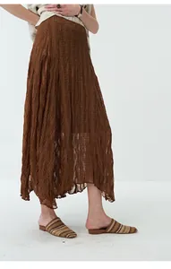 Macro view of the pleated fabric texture and asymmetric hem of the brown maxi skirt