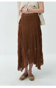 Close-up of brown pleated midi skirt featuring textured fabric and an asymmetrical hem