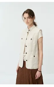 Full body view of a pleated brown textured maxi skirt styled with a beige linen vest.