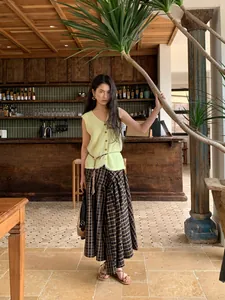 Elegant light yellow knitted sleeveless mesh vest for women shown in a rustic cafe setting