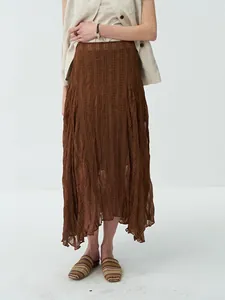 Elegant brown pleated asymmetrical hem midi skirt featuring textured fabric for beach