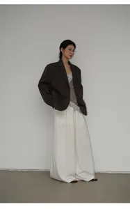 Inquadratura a figura intera di un blazer marrone scuro oversize con pantaloni bianchi