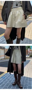 Streetstyle-opname van glanzende beige imitatielederen korte broek met wijde pijpen