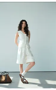 Modelo asiática con pantalones cortos blancos línea A y chaleco de punto en estudio mínimo.
