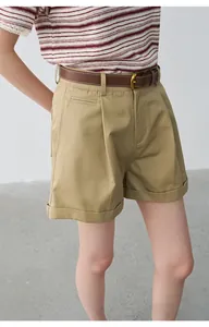 Detail shot of women's pleated khaki shorts with rolled cuffs and brown belt