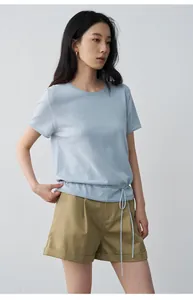 Side view showing details of khaki pleated shorts with rolled-hem and light blue knit top