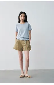 Professional full-length view of a model wearing pleated mid-waist khaki casual shorts.
