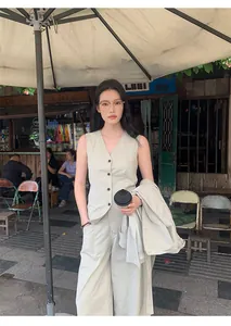 Elegant woman wearing minimalist high-waisted wide-leg trousers in an outdoor cafe set.