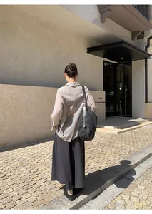 Achteraanzicht van een vrouw in een casual grijze wijde korte broek in een minimalistische setting.
