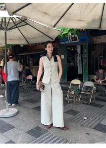 Elegant Asian model in minimalist high-waisted wide-leg pants and matching vest outdoors