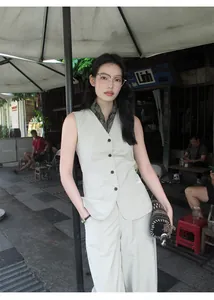 Model wearing minimalist high-waisted beige wide-leg trousers in an outdoor setting