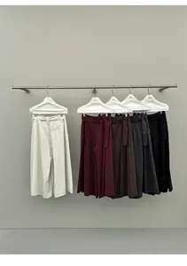 Detail van wijde broeken met hoge taille in herfstkleuren aan een minimalistisch kledingrek