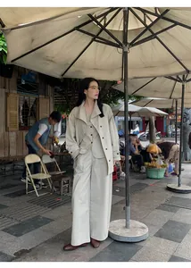 Full body view of a woman in a minimalist beige three-piece suit with wide-leg pants.