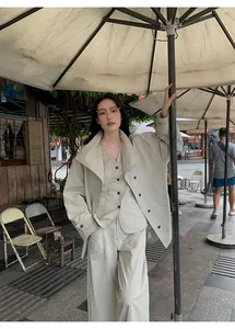 Professional model wearing a minimalist beige cotton blend jacket and wide leg trousers