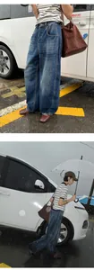 Lifestyle-Aufnahme einer blauen Retro-Jeans mit weitem Bein in regnerischer Straße.