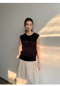 Detail view of model wearing a black linen blend sleeveless knitted top in soft lighting