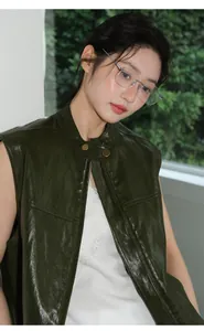 Detailansicht einer dunkelgrünen Damen-Lederweste mit Silberbrille und Spitzenoberteil
