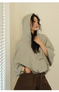 Side view of women's oversized grey hooded sweatshirt featuring unique mesh layer detail