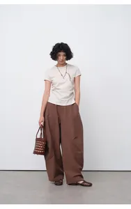 Full view of a female model wearing a white pleated slim-fit T-shirt with a necklace