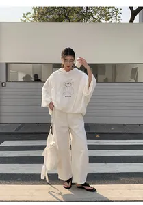 Oversized white hooded sweatshirt with graphic print shown in an urban setting
